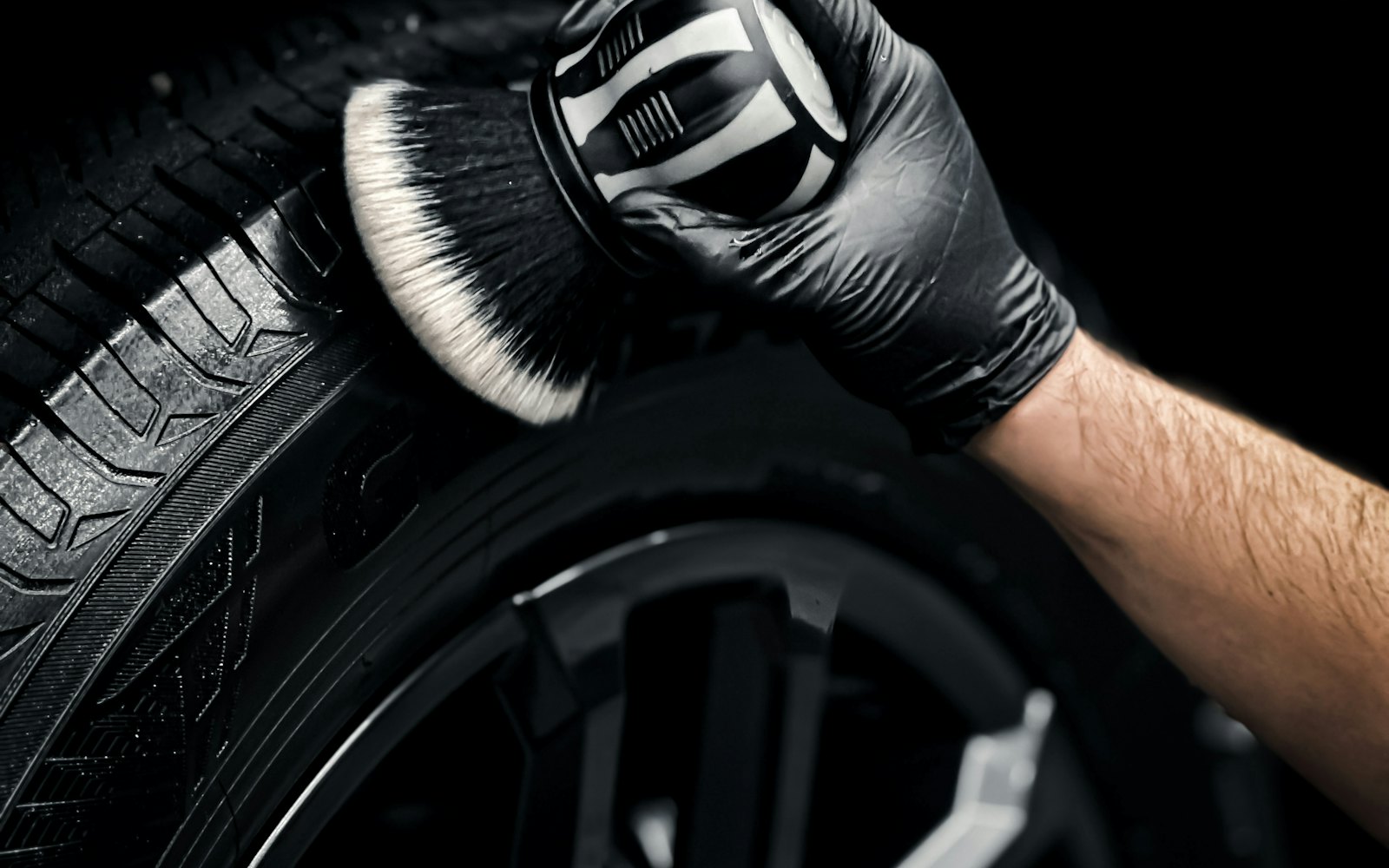Detailer cleaning a car wheel with a brush