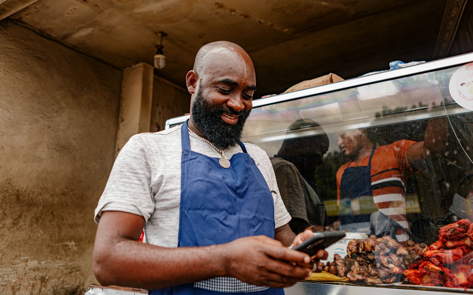 Small business owner in an apron checking his phone