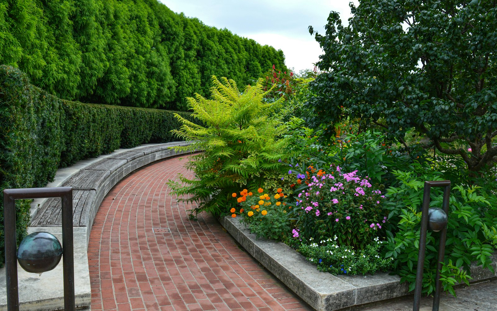 Brick garden path lined with flowers and shrubs