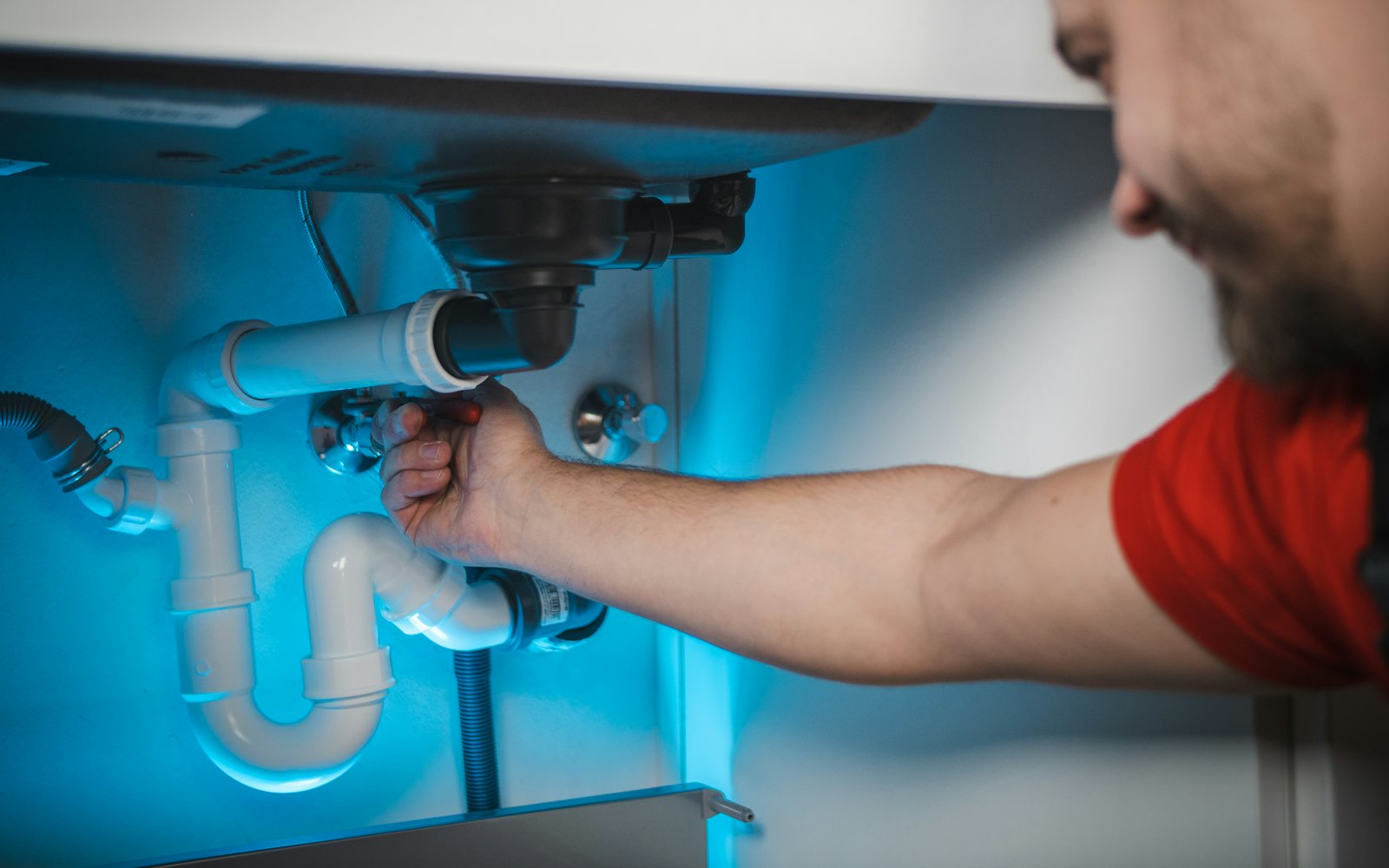 Plumber working on pipework behind a wall